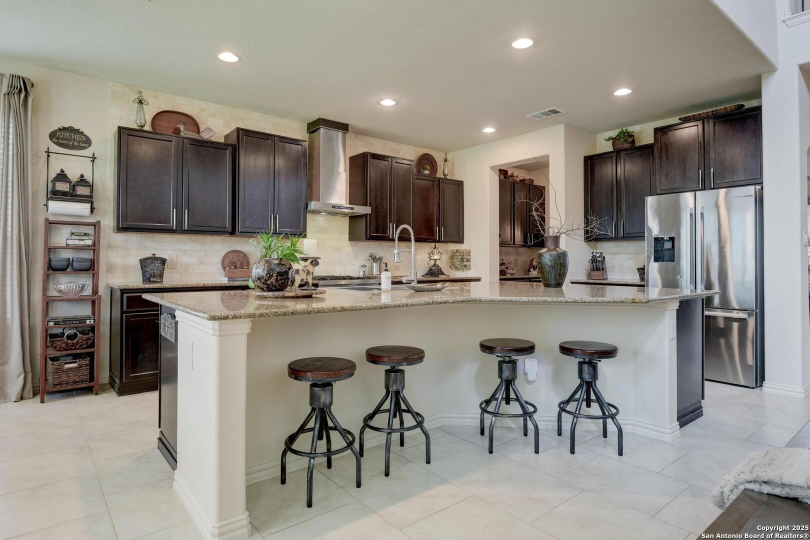 a kitchen with kitchen island granite countertop wooden cabinets and refrigerator
