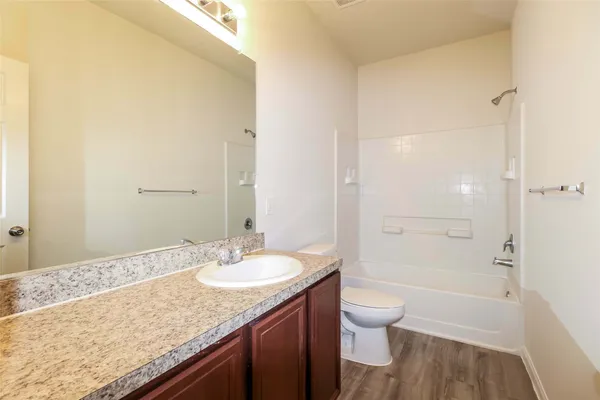 a bathroom with a granite countertop sink a toilet and shower