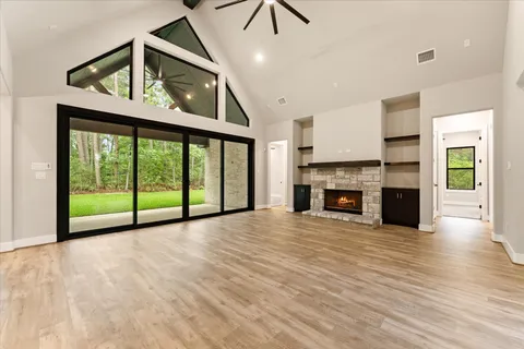 a view of an empty room with wooden floor fireplace and a window