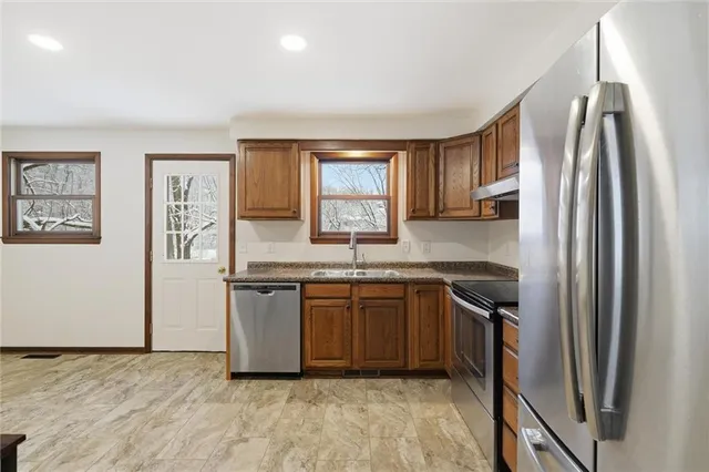 a kitchen with stainless steel appliances granite countertop a refrigerator sink and stove