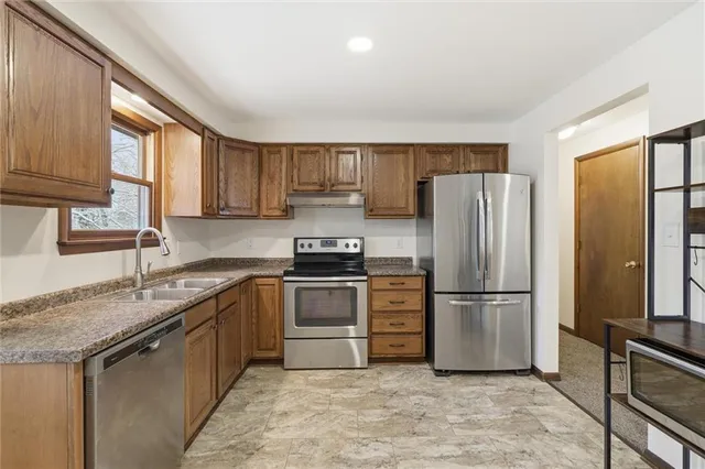 a kitchen with granite countertop a refrigerator and a sink
