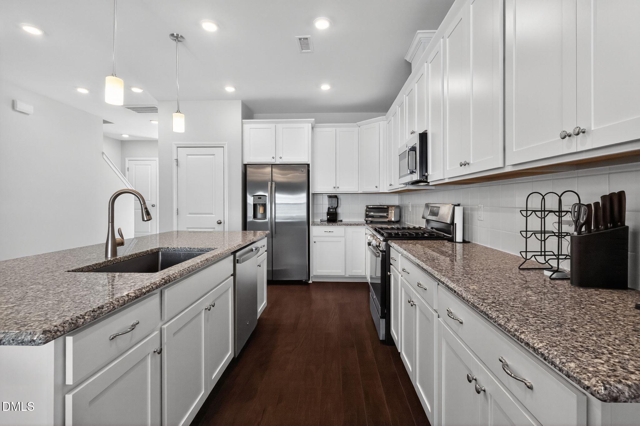 1118 Commack Drive Durham, NC 27703 - Photo 7 of 30 a kitchen with granite countertop kitchen island a sink stainless steel appliances and window