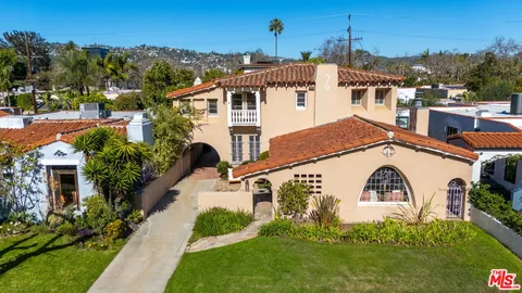 a view of a white house next to a yard with potted plants