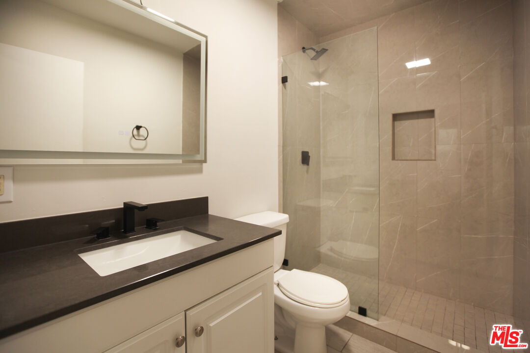 1323 South Ridgeley Drive, Unit 2 Los Angeles, CA 90019 - Photo 8 of 11 a bathroom with a sink a toilet a shower and a mirror