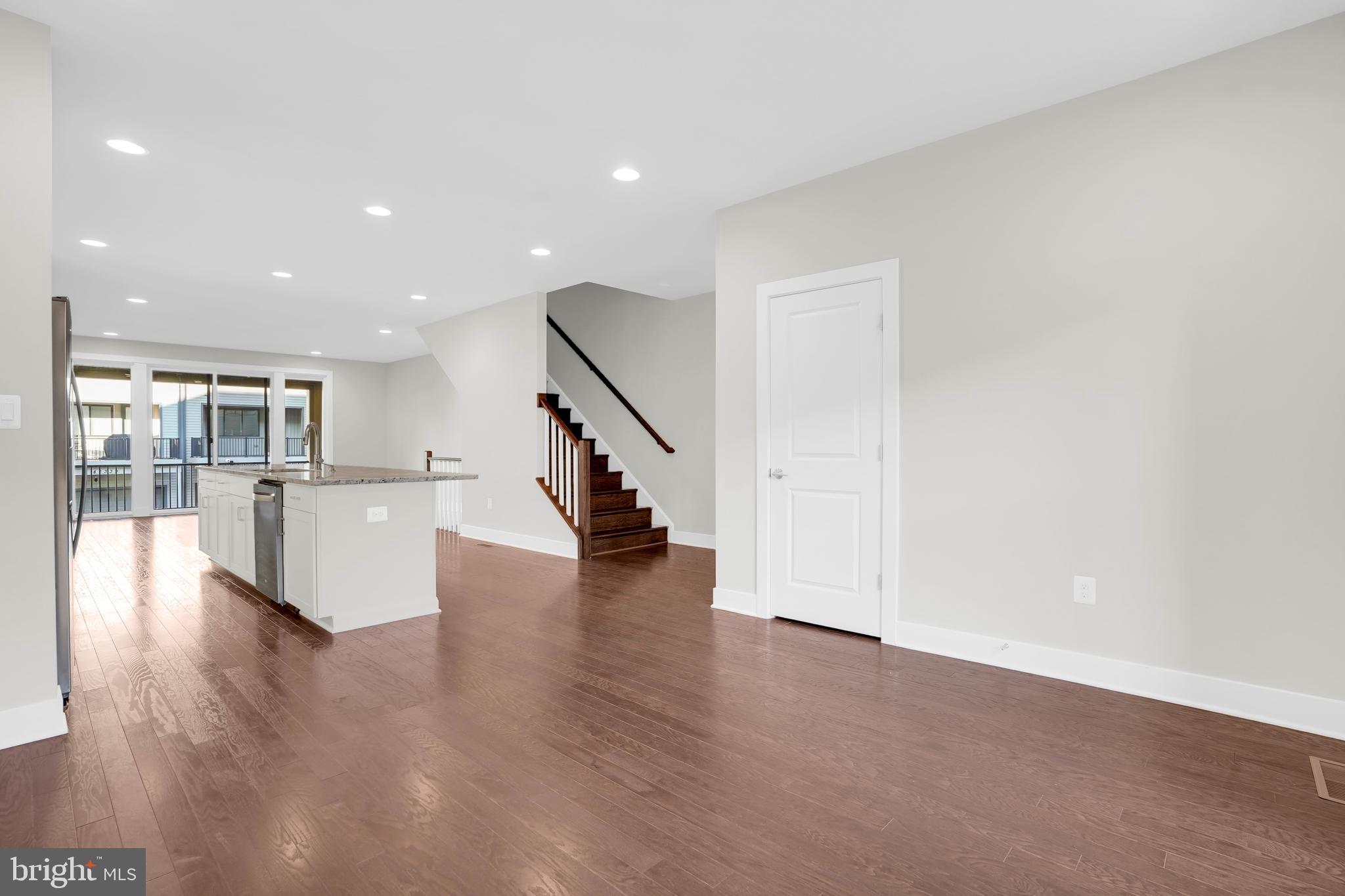 22954 Sullivans Cove Square Brambleton, VA 20148 - Photo 13 of 38 a view of an empty room with wooden floor and a kitchen