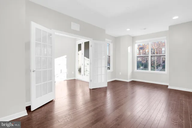 a view of an empty room with window and wooden floor