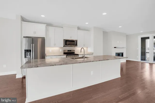 a large kitchen with granite countertop a large counter top stainless steel appliances and cabinets