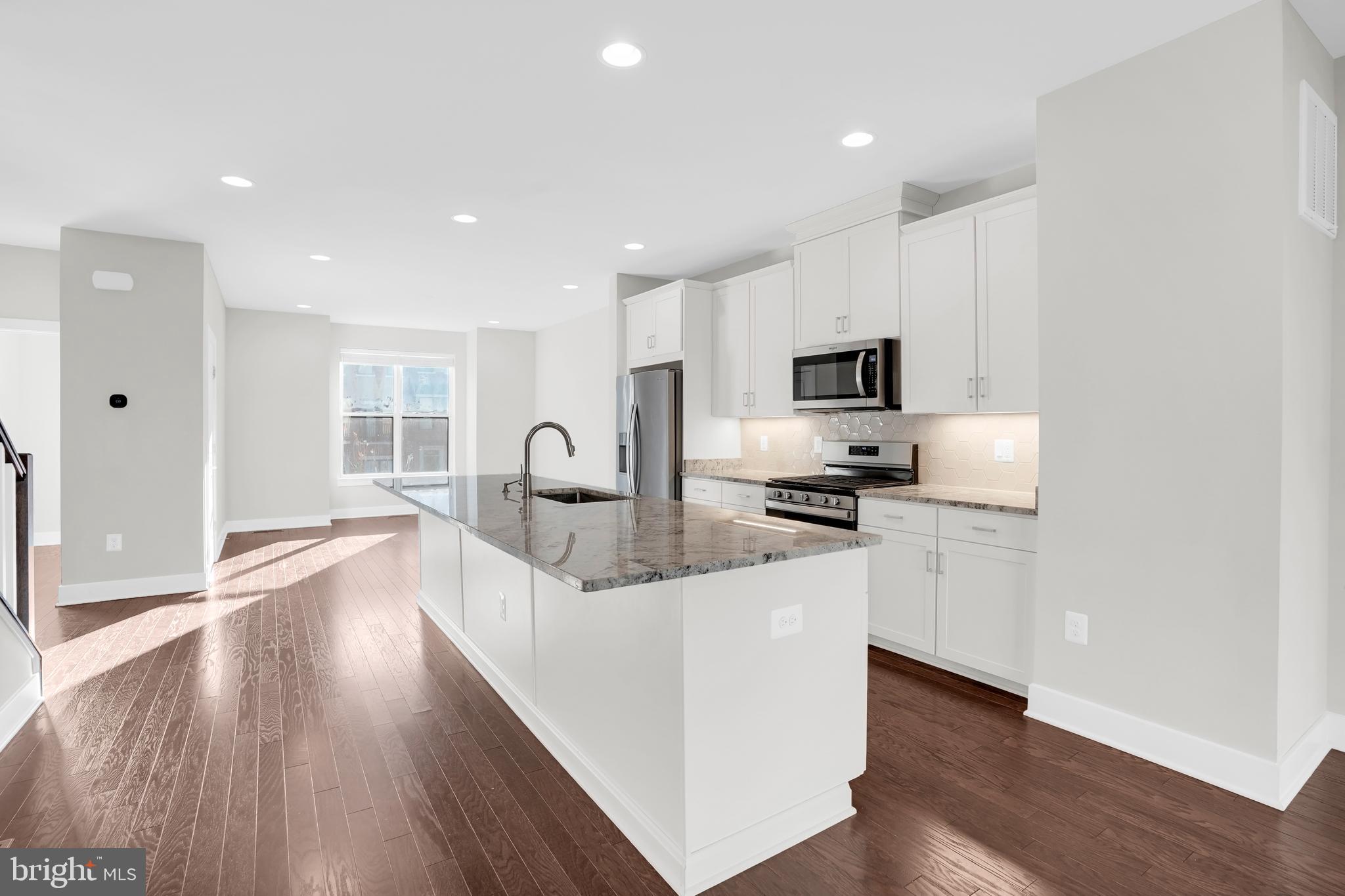 22954 Sullivans Cove Square Brambleton, VA 20148 - Photo 8 of 38 a kitchen with granite countertop a stove top oven a sink a counter space and cabinets