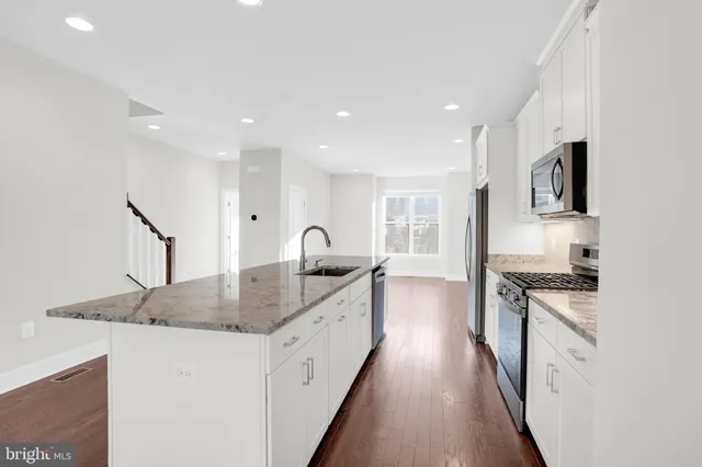 a kitchen with granite countertop a sink stove and refrigerator