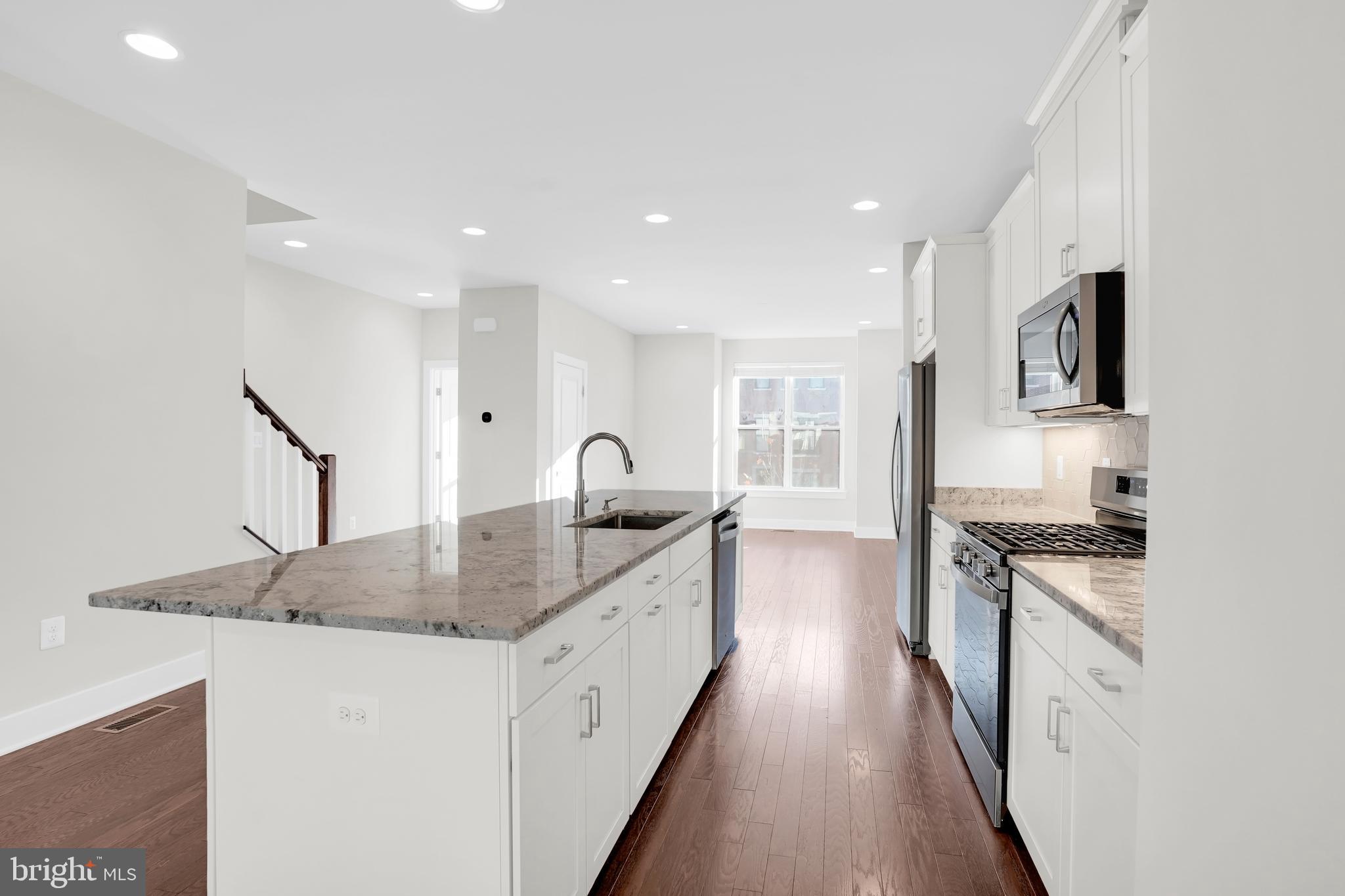 22954 Sullivans Cove Square Brambleton, VA 20148 - Photo 9 of 38 a kitchen with granite countertop a sink stove and refrigerator