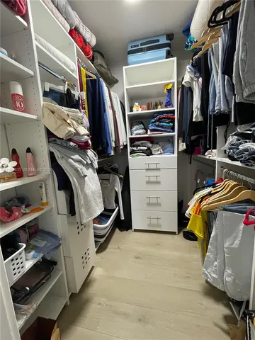 a view of walk in closet with clothes and shoes