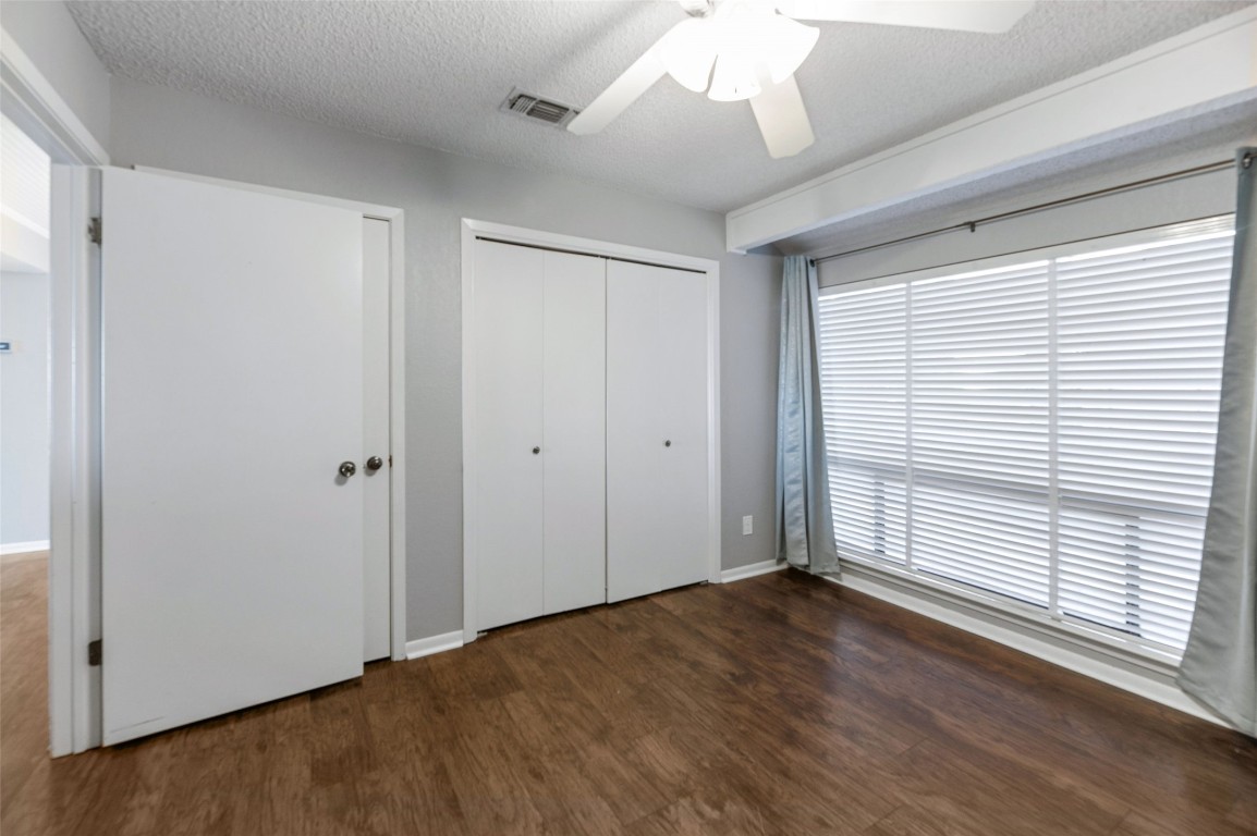 409 Hi There, Unit M Horseshoe Bay, TX 78657 - Photo 14 of 33 Unfurnished bedroom featuring a textured ceiling, dark wood-style flooring, ceiling fan, and a closet