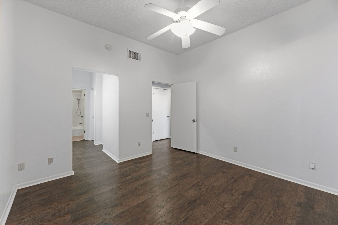 409 Hi There, Unit M Horseshoe Bay, TX 78657 - Photo 20 of 33 Unfurnished bedroom featuring dark wood-style floors, ceiling fan, and ensuite bathroom