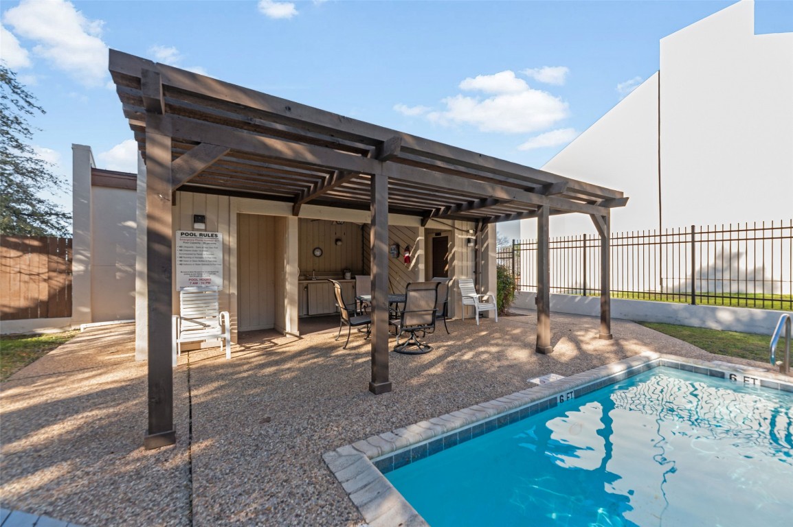 409 Hi There, Unit M Horseshoe Bay, TX 78657 - Photo 26 of 33 Rear view of house with a pergola, a community pool, outdoor dining area, and a patio area