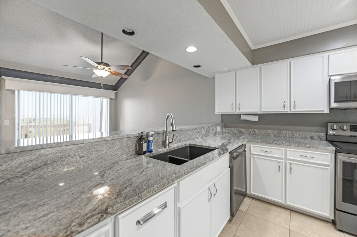 409 Hi There, Unit M Horseshoe Bay, TX 78657 - Photo 6 of 33 Kitchen with stainless steel appliances, white cabinetry, light stone countertops, light tile patterned floors, and a ceiling fan