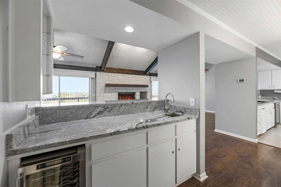 409 Hi There, Unit M Horseshoe Bay, TX 78657 - Photo 9 of 33 Kitchen featuring white cabinets, light stone countertops, wine cooler, a fireplace, and recessed lighting