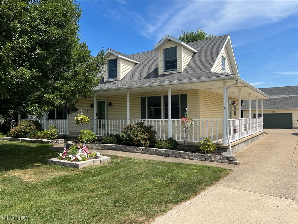 5912 Coen Road Vermilion, OH 44089 - Photo 2 of 28 Country-style home featuring a porch, a garage, a front yard, roof with shingles, and concrete driveway