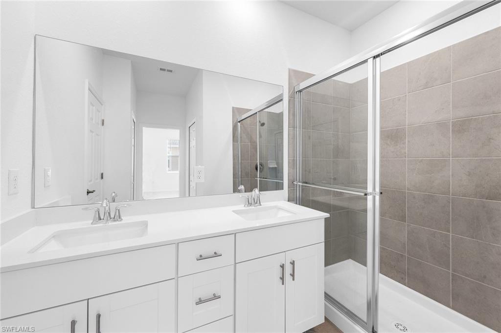 2827 Blossom Way Naples, FL 34120 - Photo 12 of 31 Bathroom featuring double vanity and a shower stall
