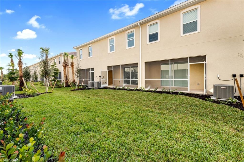 2827 Blossom Way Naples, FL 34120 - Photo 17 of 31 Back of house featuring stucco siding, a yard, and a sunroom