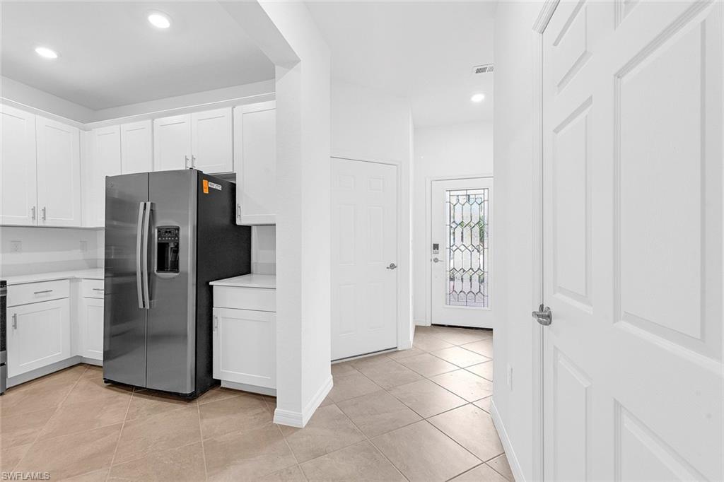 2827 Blossom Way Naples, FL 34120 - Photo 5 of 31 Kitchen with stainless steel refrigerator with ice dispenser, white cabinetry, recessed lighting, and light tile patterned floors