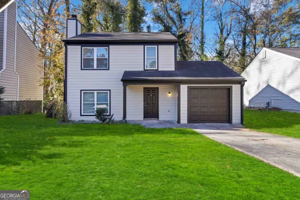 a view of a yard in front of a house with plants and large tree