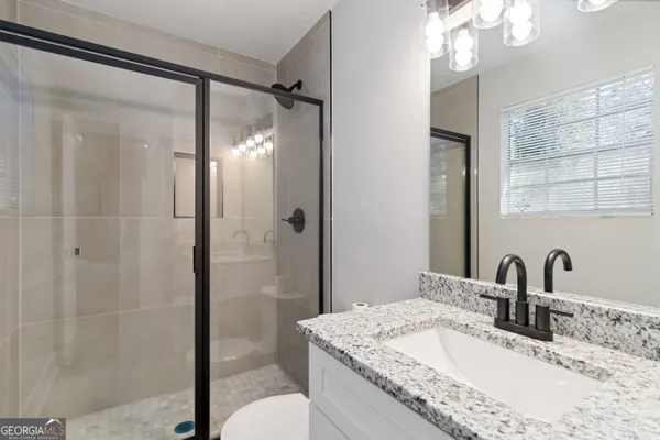 a bathroom with a granite countertop sink mirror and shower