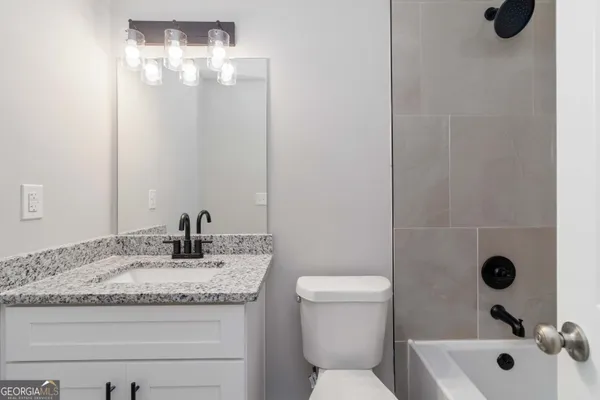 a bathroom with a granite countertop sink a toilet and mirror