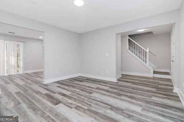 a view of an empty room with wooden floor and stairs