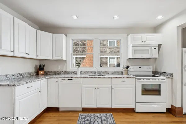 a kitchen with granite countertop white cabinets and white appliances
