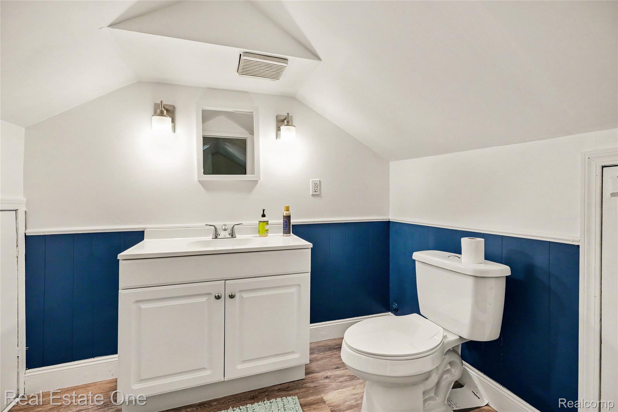 2073 Roslyn Road Grosse Pointe, MI 48236 - Photo 21 of 30 Bathroom featuring a white vanity with a single basin sink, white toilet, wood-finish flooring, and blue wainscoting