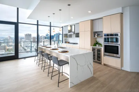 a kitchen with stainless steel appliances kitchen island granite countertop a stove a refrigerator a dining table and chairs with wooden floor