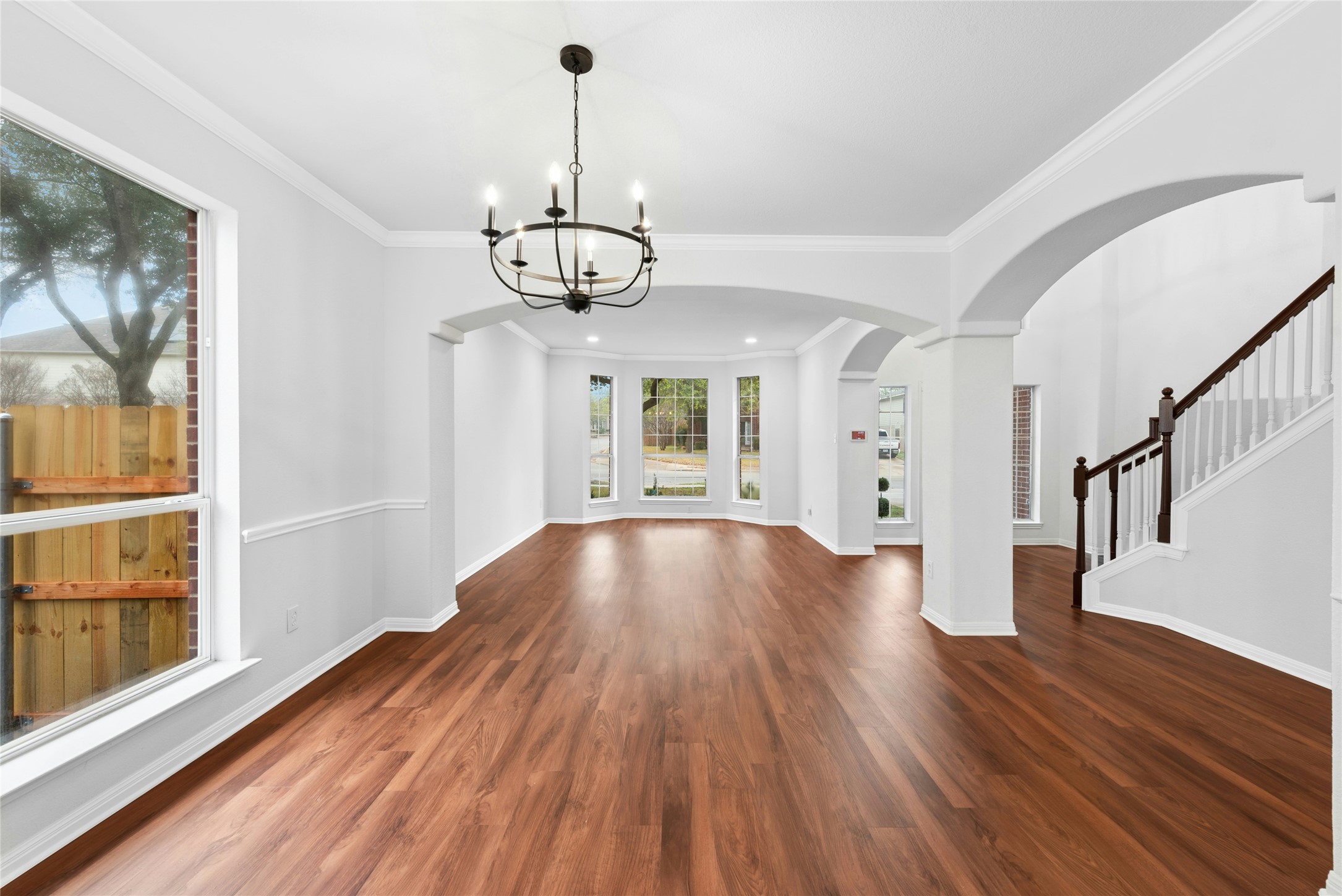 813 Caribou Ridge Trail Pflugerville, TX 78660 - Photo 11 of 39 Beautiful dining space with arched walkways, detailed molding, warm luxury vinyl plank flooring, and a modern chandelier that adds elegance and style.