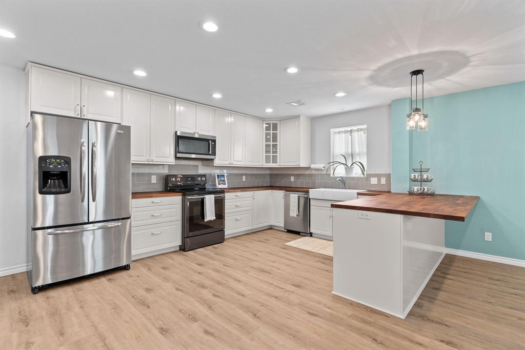 1206 Jc Maples Road Gunter, TX 75058 - Photo 29 of 40 a kitchen with stainless steel appliances granite countertop a refrigerator a sink dishwasher a stove and white cabinets with wooden floor