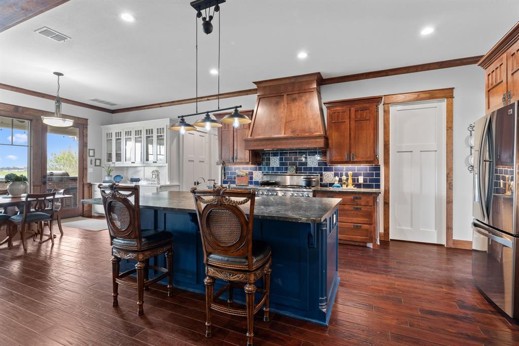 1206 Jc Maples Road Gunter, TX 75058 - Photo 6 of 40 a open kitchen with stainless steel appliances granite countertop a stove a refrigerator a kitchen island a dining table and chairs with wooden floor