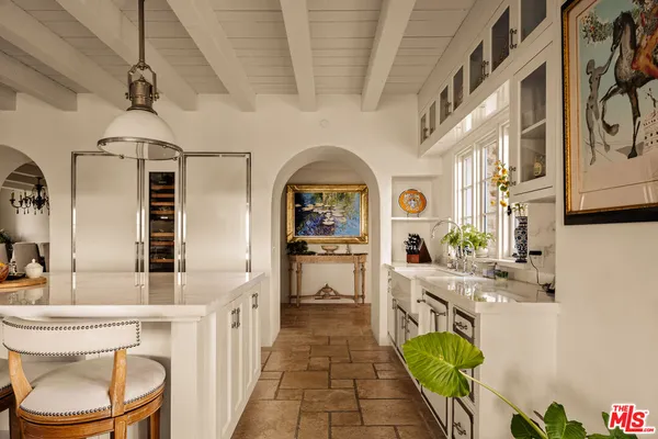 a living room with stainless steel appliances furniture a chandelier and a kitchen view