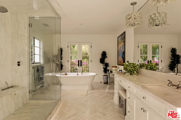 a large white bathroom with a sink a large mirror and a bathtub