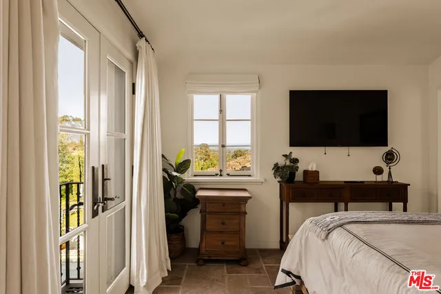 a bedroom with a bed and a flat tv screen on dresser