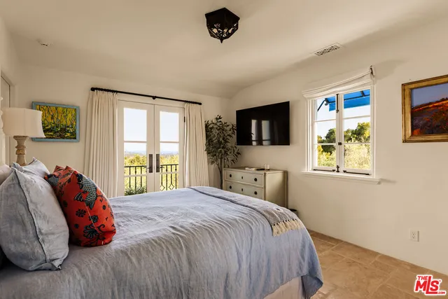 a bedroom with a bed a window and flat screen tv