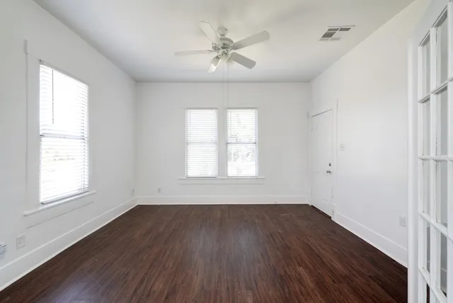 a view of an empty room with wooden floor and a window
