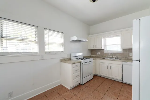 a kitchen with white cabinets appliances and a window