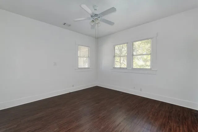 an empty room with wooden floor and windows