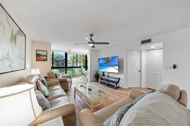 a living room with furniture a ceiling fan and a flat screen tv