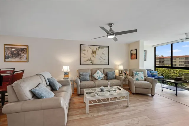 a living room with furniture ceiling fan and a large window