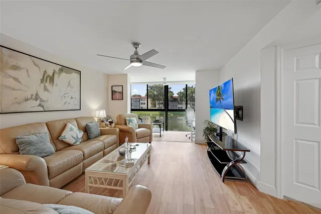 a living room with furniture a flat screen tv and a ceiling fan