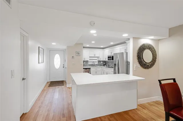 a large kitchen with a wooden floor and white cabinets