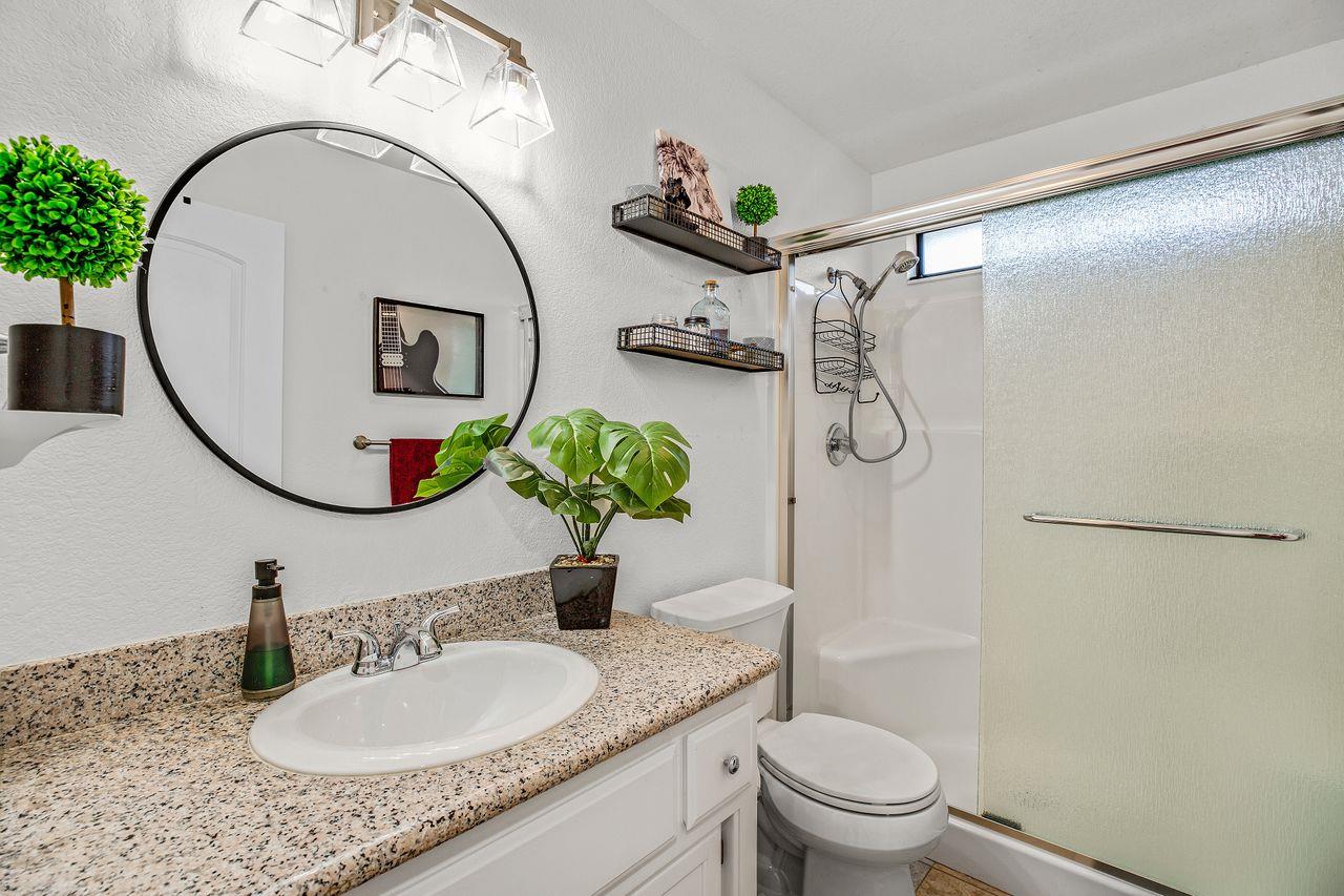 17745 Park Way Morgan Hill, CA 95037 - Photo 26 of 36 a bathroom with a granite countertop sink a mirror a toilet and a shower