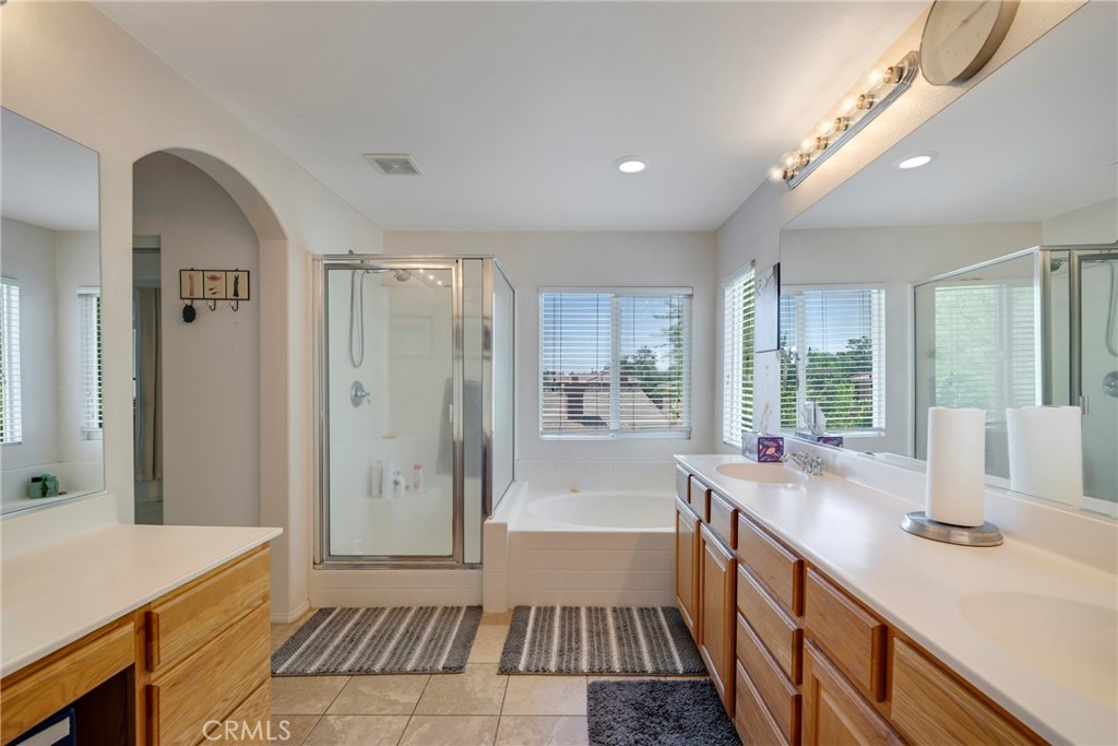 3819 St Austell Way Perris, CA 92571 - Photo 46 of 64 a bathroom with a sink a large mirror a bathtub and a shower