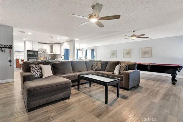 a living room with furniture kitchen view and a chandelier
