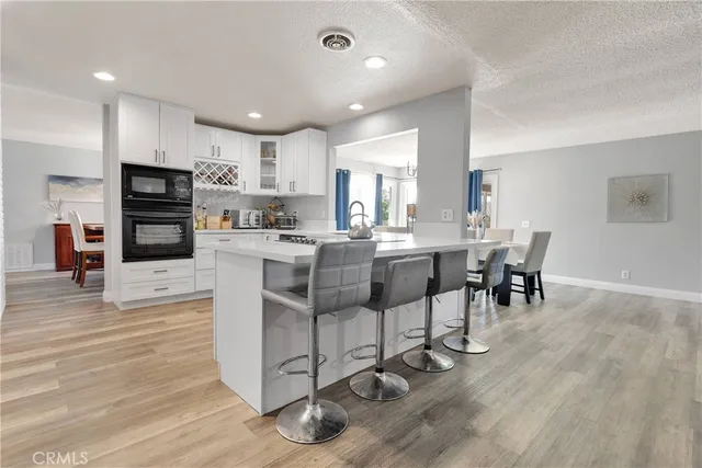 a kitchen with stainless steel appliances granite countertop a stove top oven a sink dishwasher a dining table and chairs with wooden floor