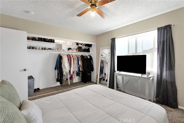a view of a bedroom with a flat tv screen and a ceiling fan